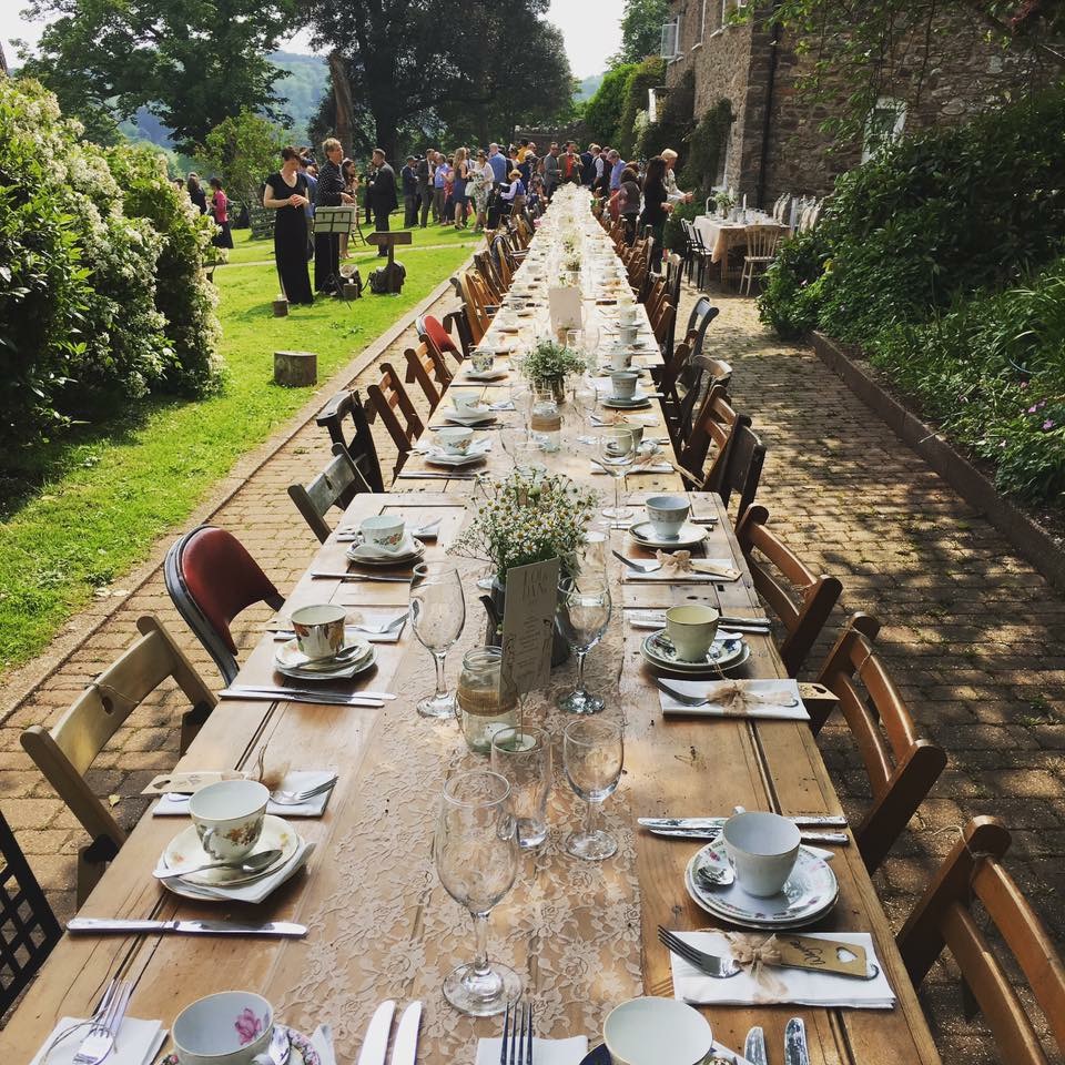 a long table set up for afternoon tea outdoors for a wedding