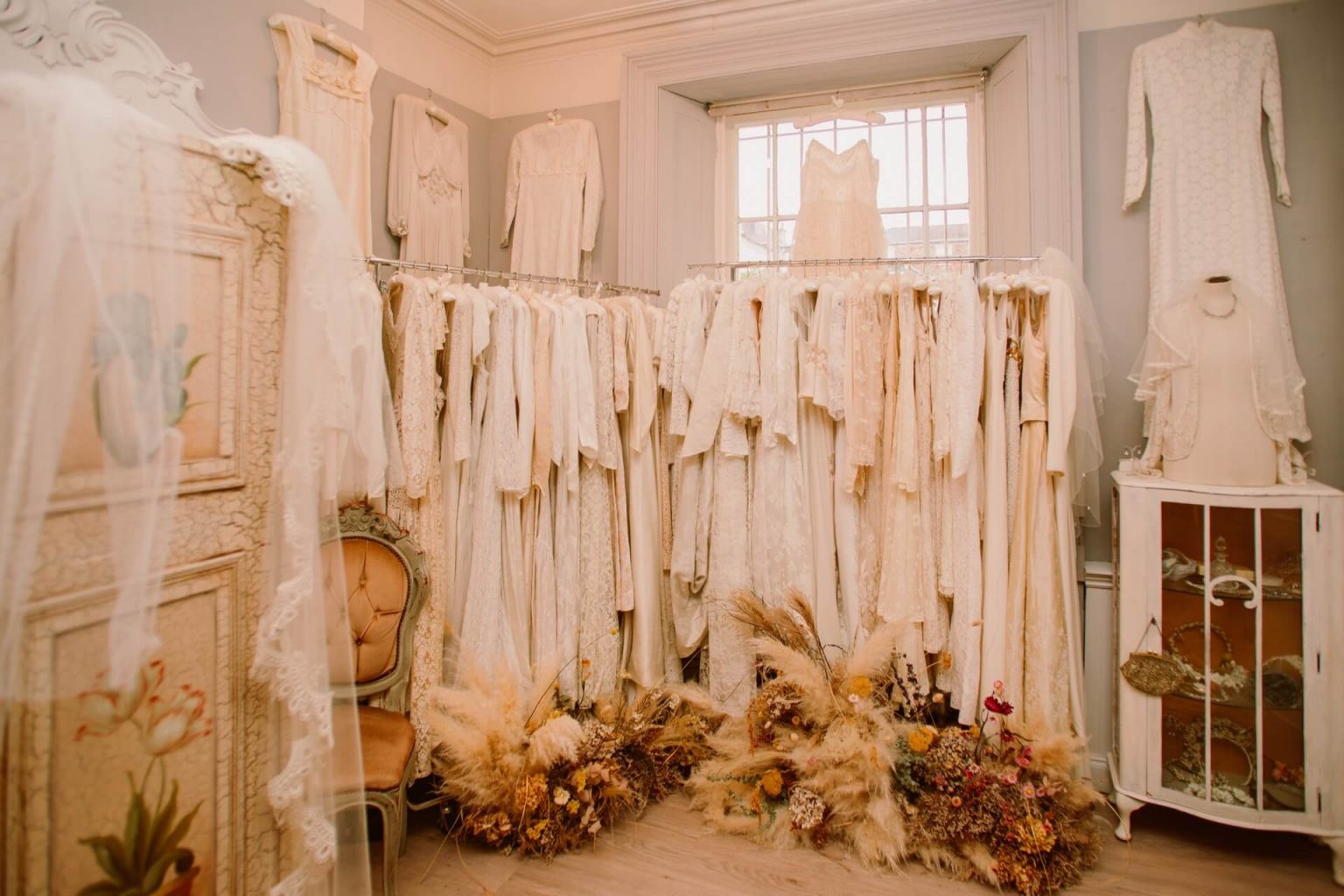 Interior shot of Ashwell & Co, with rails full of vintage wedding dresses and beautiful dried flowers