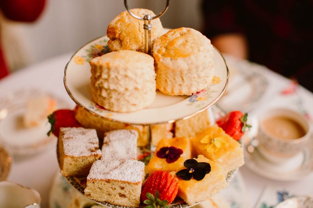large vintage cake stand filled with cake, scones and fruit for afternoon tea