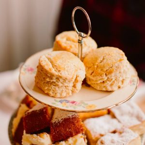 large vintage cake stand filled with cake, scones and fruit for afternoon tea