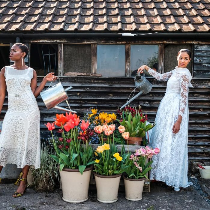 Two brides wearing Ashwell & Co vintage wedding dresses watering flowers at Court House Farm